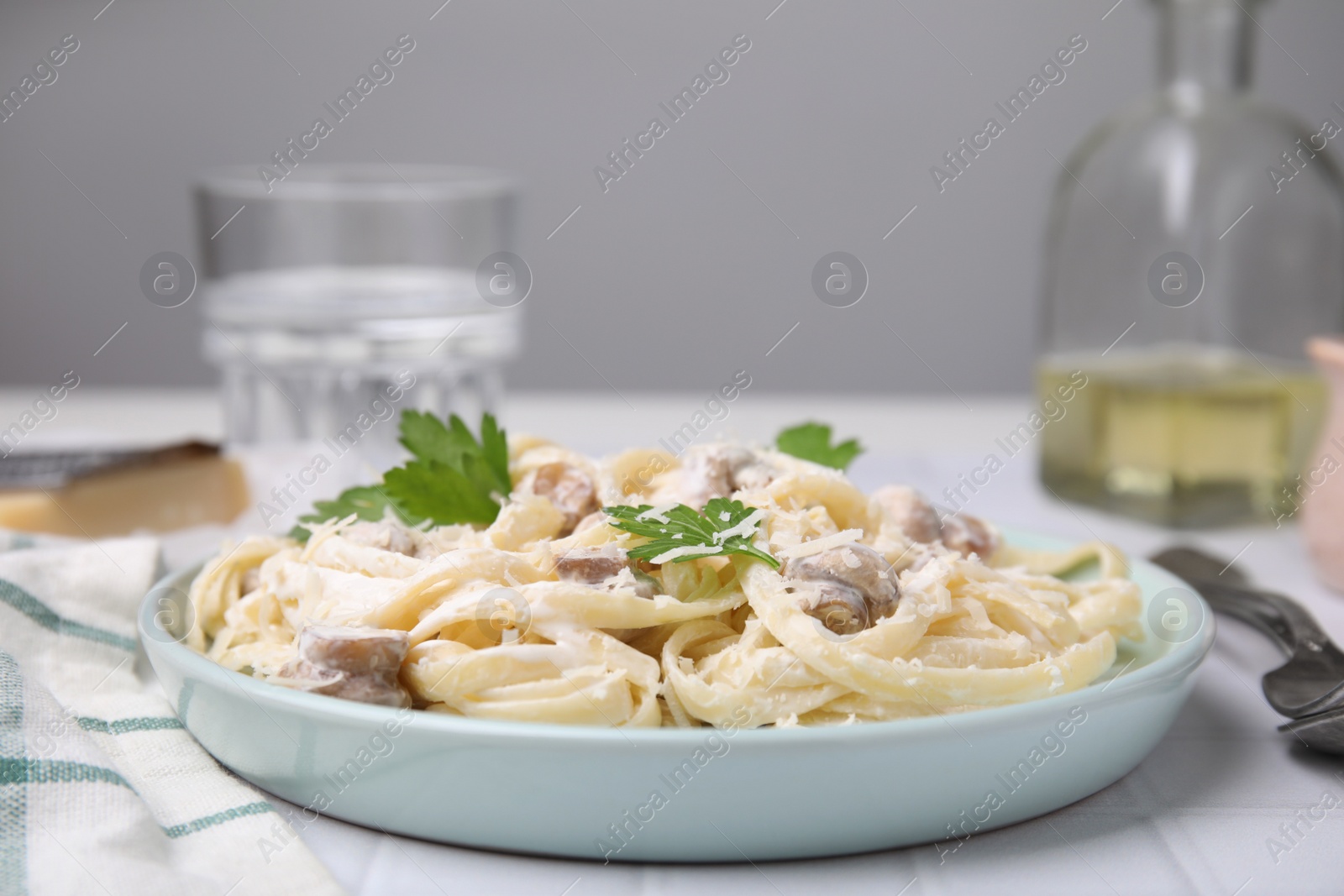 Photo of Delicious pasta with mushrooms on white tiled table, closeup