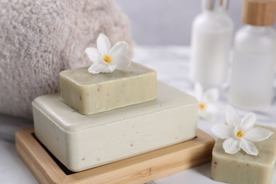 Spa composition with soap, flowers and towel on white table, closeup