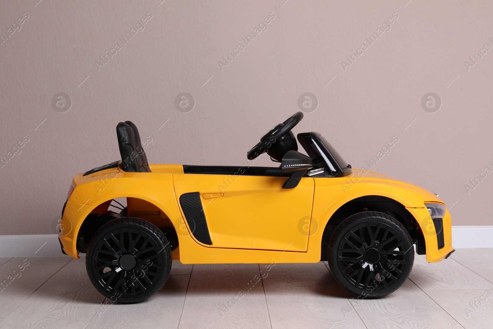 Photo of Child's electric toy car near beige wall indoors