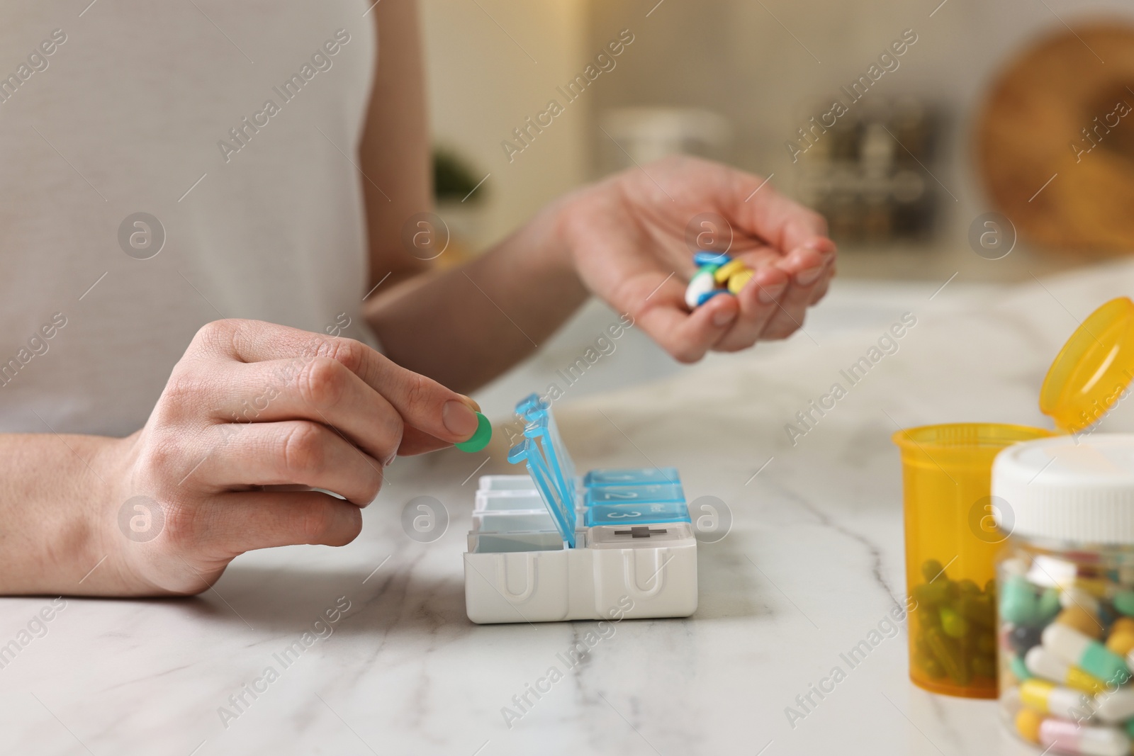 Photo of Woman with pills and organizer at white marble table, closeup