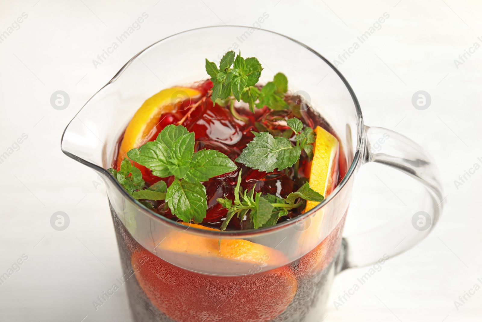 Photo of Jug with delicious refreshing cocktail on table, closeup