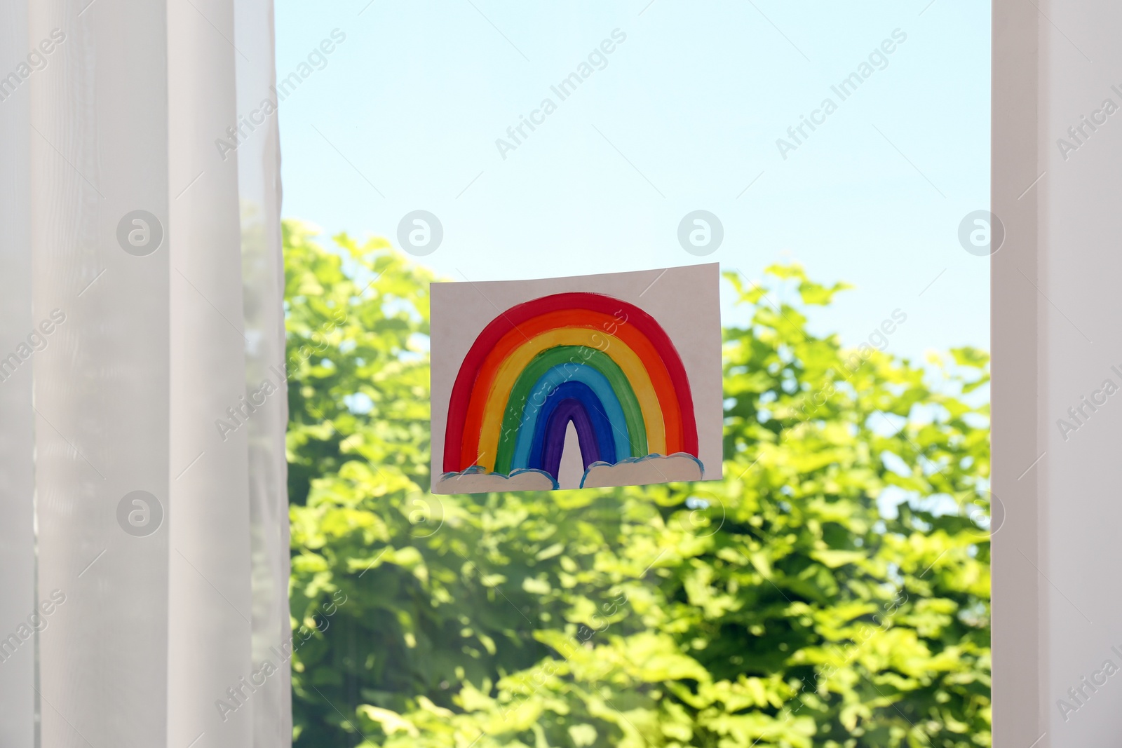 Photo of Picture of rainbow on window glass indoors. Stay at home concept