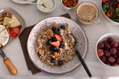 Photo of Oatmeal with fruits and nuts served on buffet table for brunch, flat lay