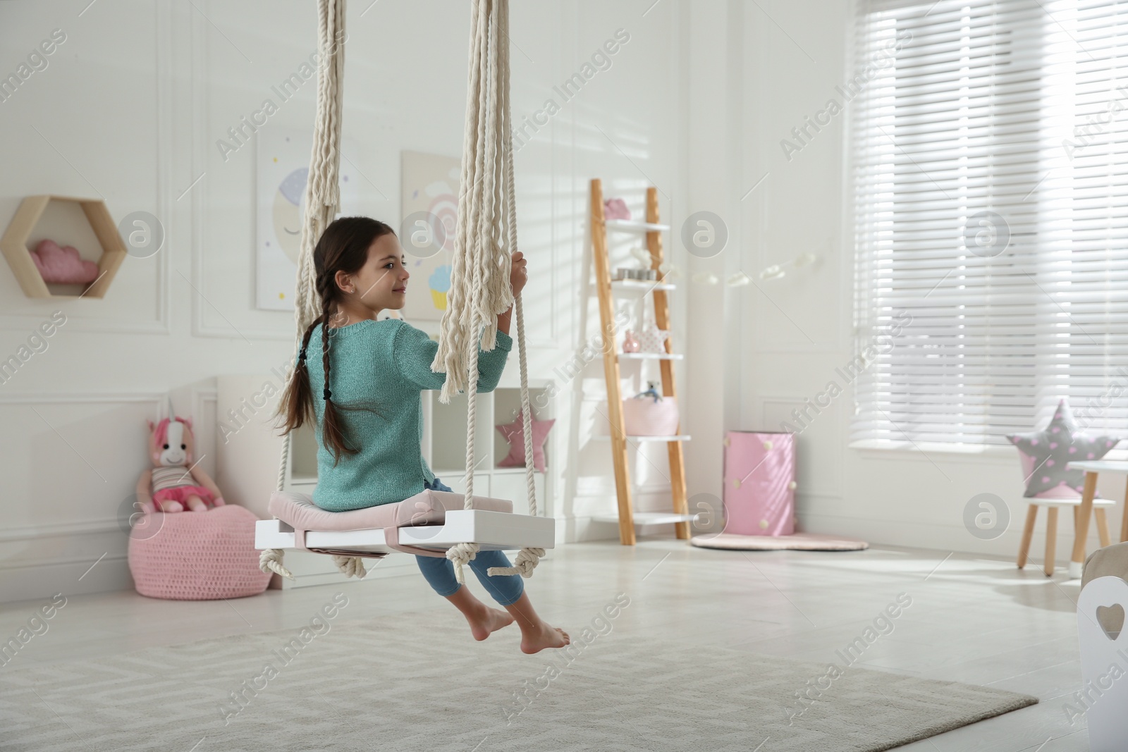 Photo of Cute little girl playing on swing at home