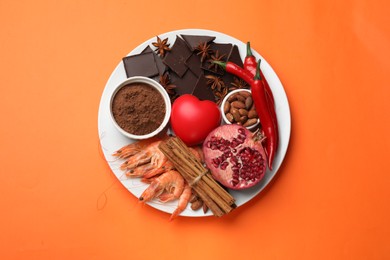 Photo of Natural aphrodisiac. Different products and heart model on orange background, top view