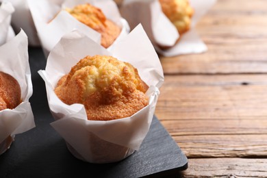 Photo of Delicious sweet muffins on wooden table, closeup. Space for text