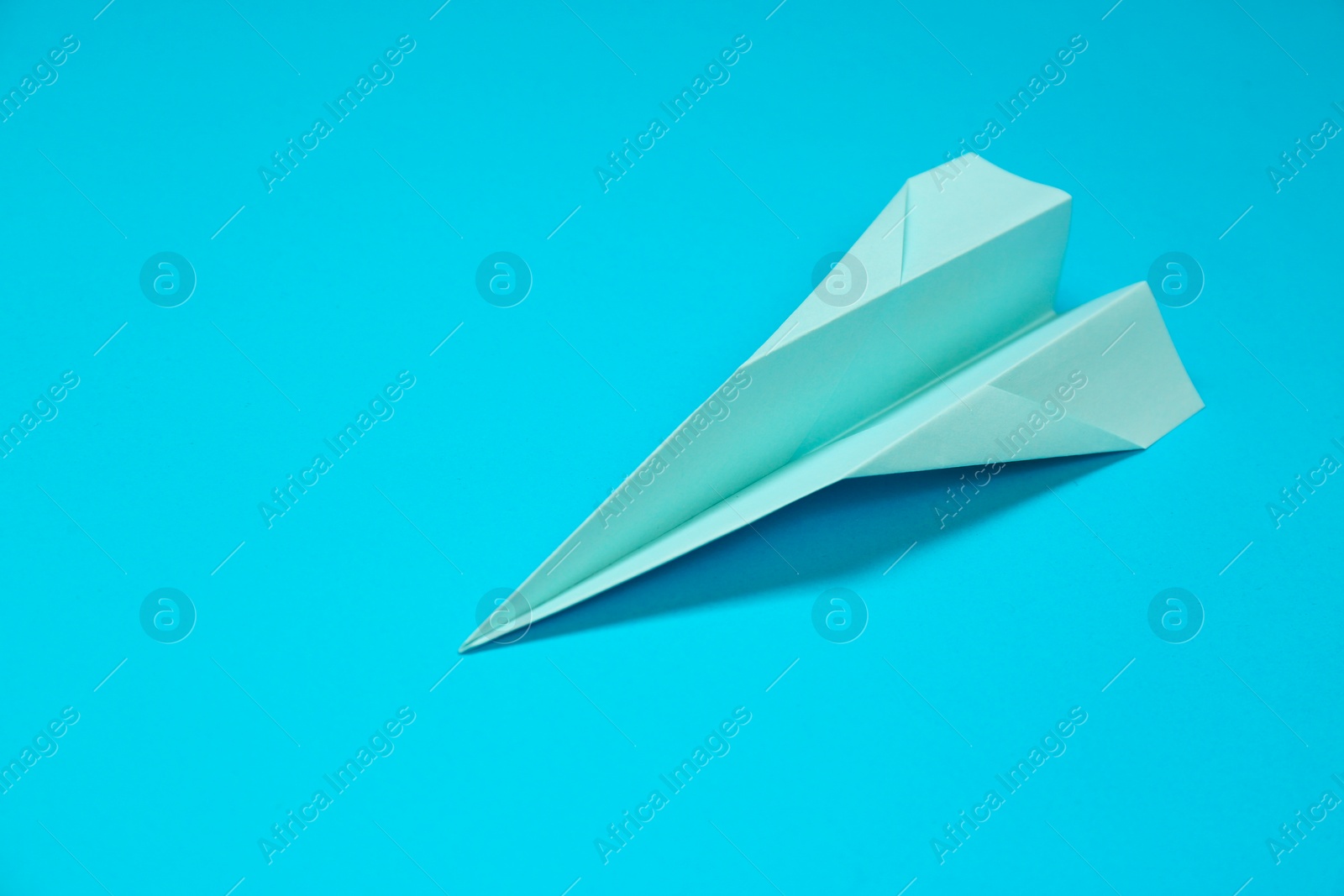 Photo of Paper plane on light blue background, space for text