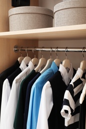 Hangers with teenage clothes on rack in wardrobe, closeup