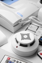 Photo of Smoke detector and remote controls on white background, closeup. Home security system