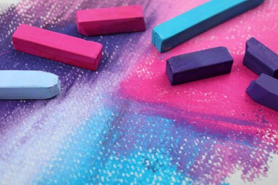 Photo of Colorful pastel chalks on abstract painting, closeup. Drawing materials