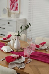 Color accent table setting. Glasses, plates, pink napkins and vase with green branch in dining room