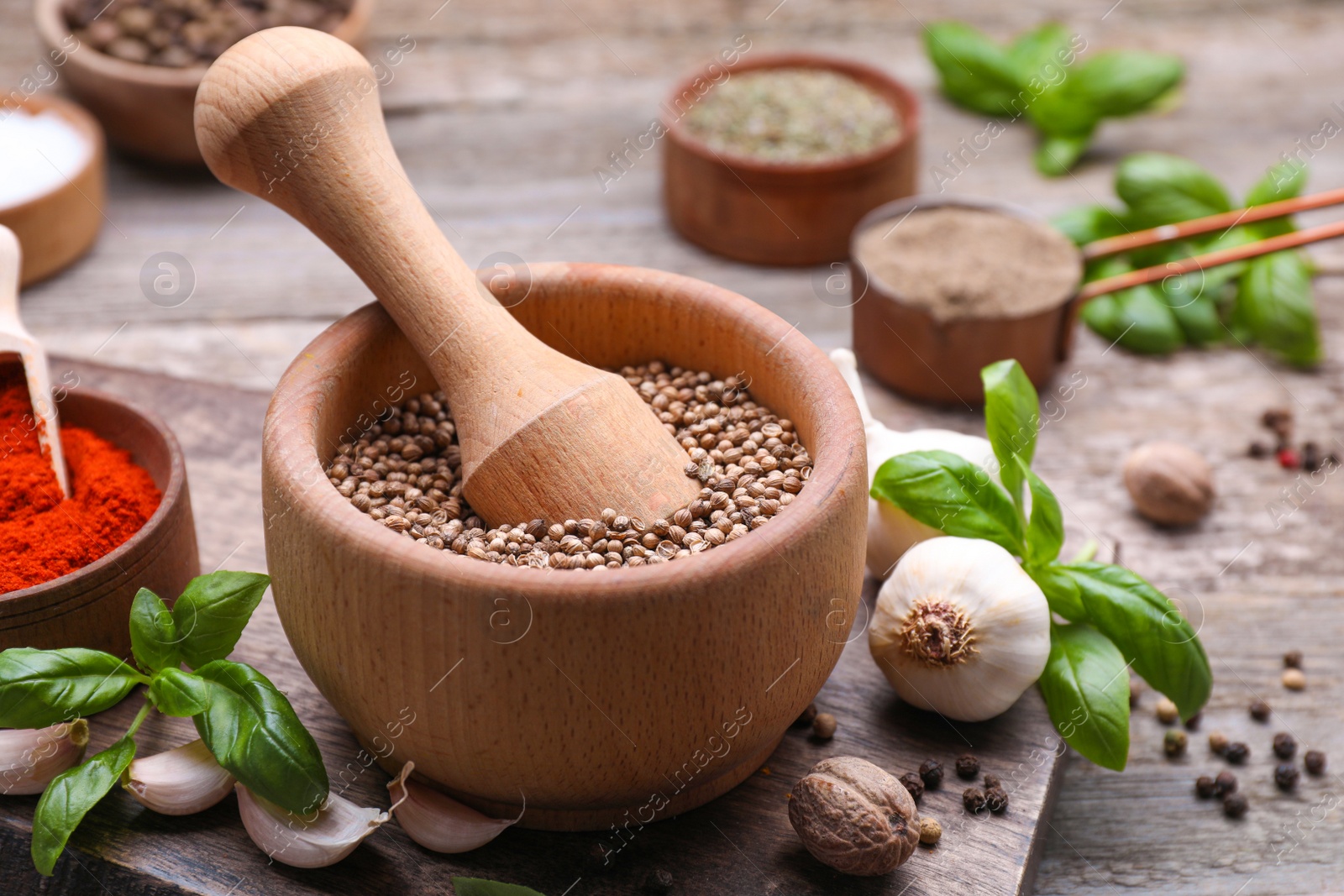 Photo of Mortar with pestle and different spices on wooden table, closeup. Space for text