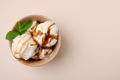 Photo of Scoopsice cream with caramel sauce and mint leaves on beige table, top view. Space for text