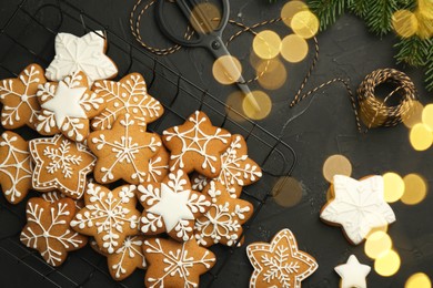 Tasty Christmas cookies with icing, scissors and spool of thread on black table, flat lay