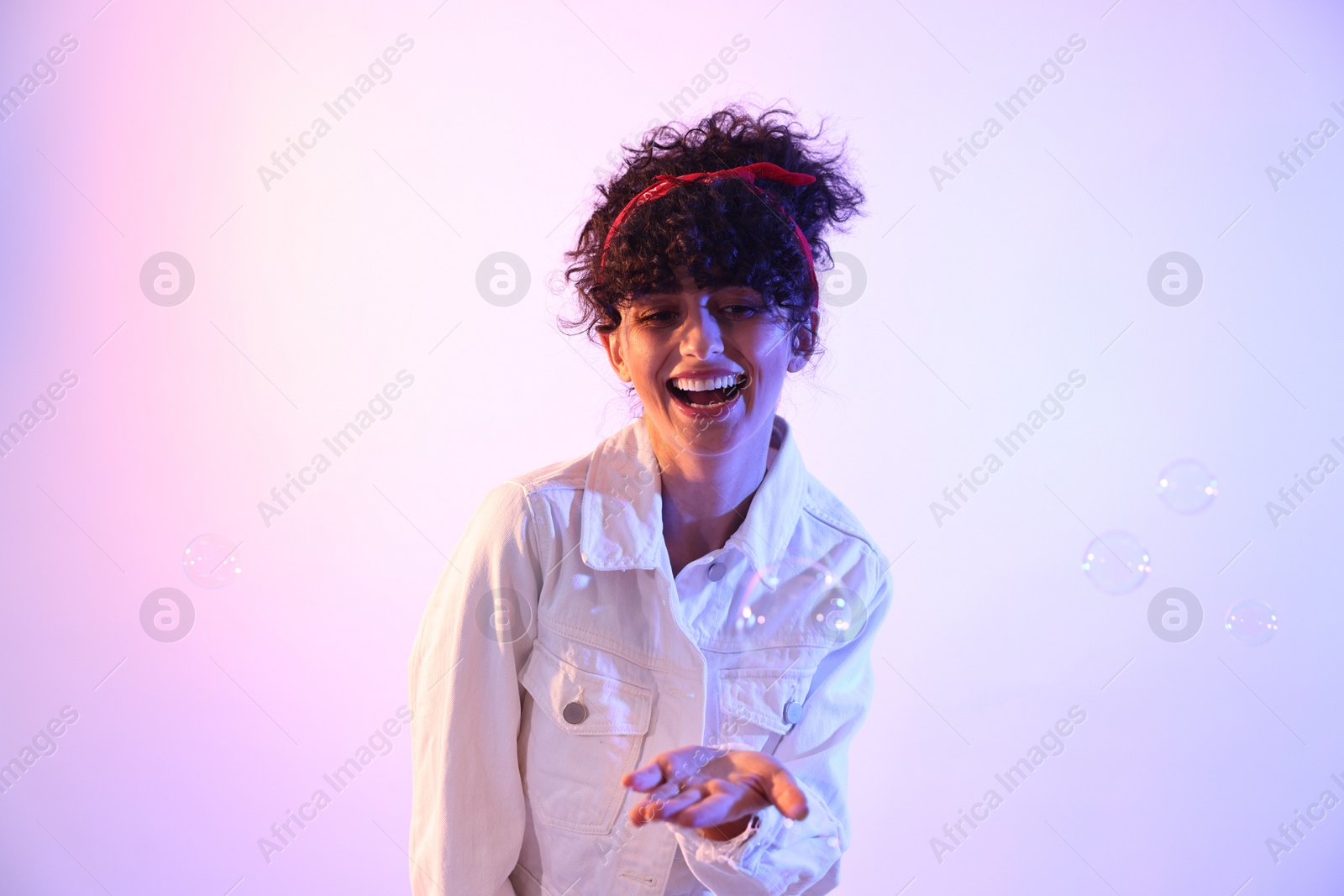 Photo of Beautiful young woman and bubbles on color background in neon lights