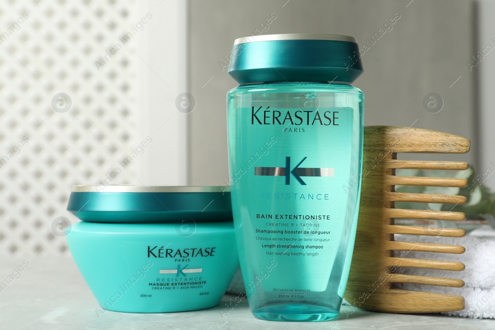 Photo of MYKOLAIV, UKRAINE - SEPTEMBER 07, 2021: Kerastase hair care cosmetic products and wooden comb on light table
