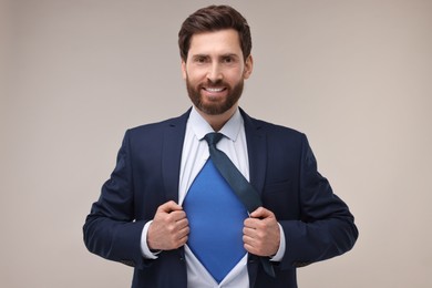 Photo of Happy businessman wearing superhero costume under suit on beige background