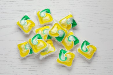 Photo of Many dishwasher detergent pods on white wooden table, flat lay