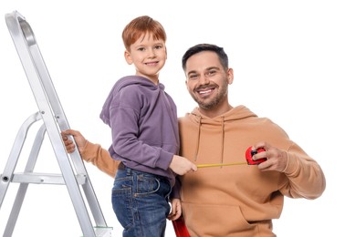 Photo of Happy family holding measuring tape near metal ladder on white background. Repair work