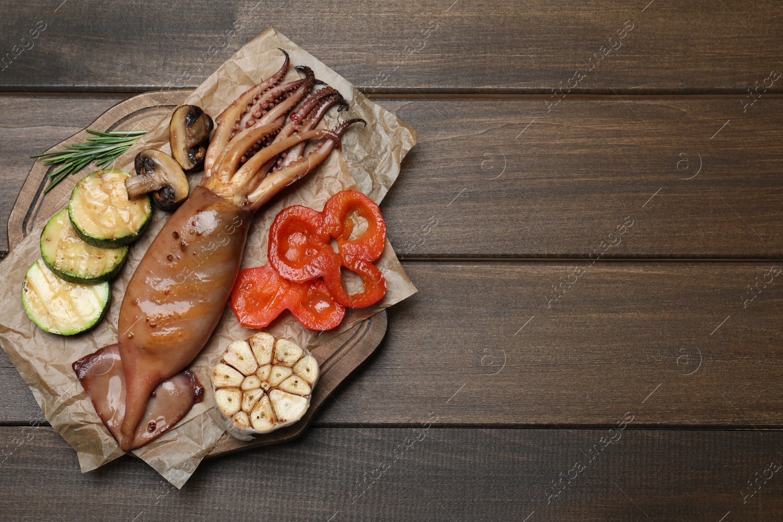 Photo of Tasty grilled squid served on wooden table, top view. Space for text