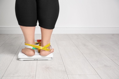 Photo of Overweight woman using scales indoors