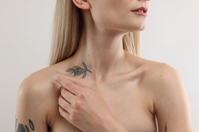 Photo of Woman with cool tattoo on light background, closeup