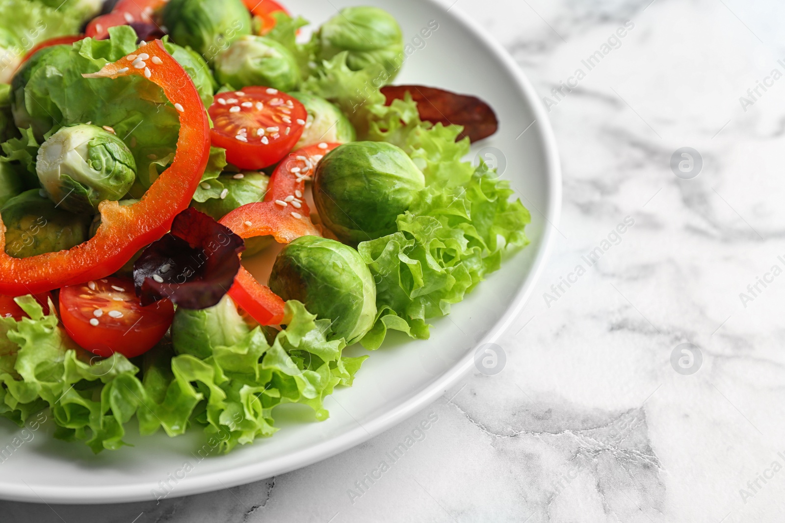 Photo of Tasty salad with Brussels sprouts on white marble table, closeup