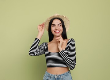 Beautiful young woman with straw hat on light green background. Space for text