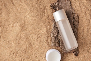 Photo of Cosmetic products and tree bark on sand, flat lay. Space for text