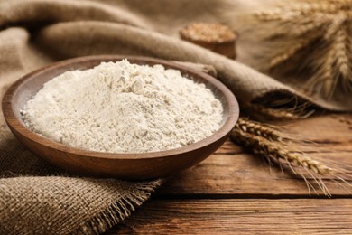 Wheat flour in bowl on wooden table