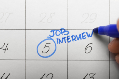 Woman marking date of job interview in calendar, closeup