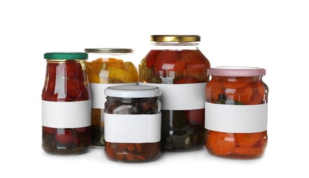Photo of Jars of pickled vegetables with blank labels on white background