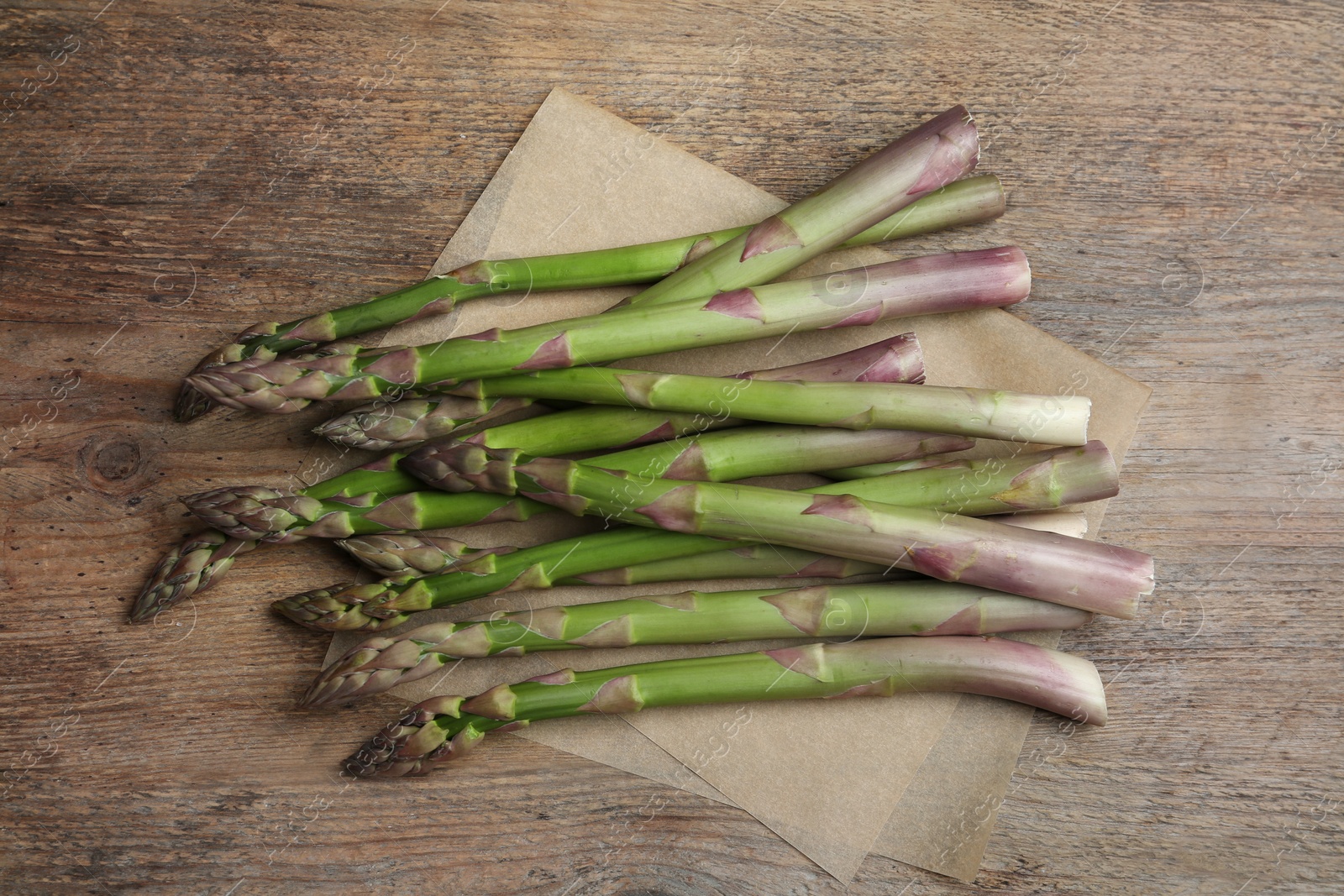 Photo of Fresh raw asparagus on wooden table, flat lay