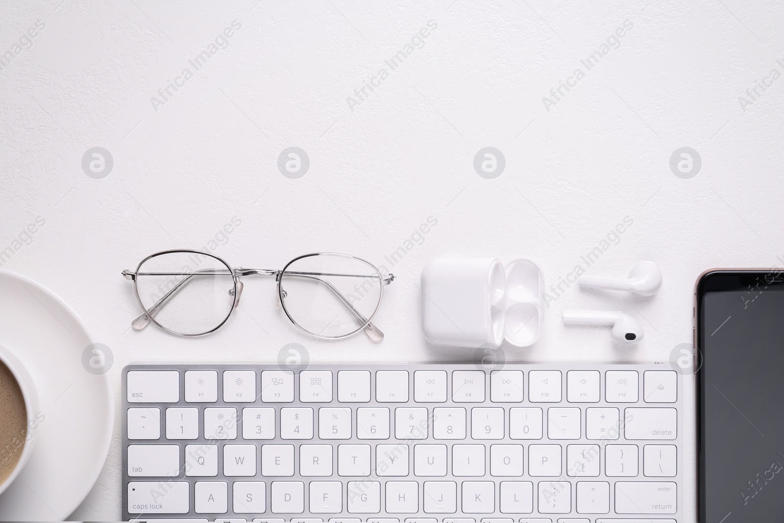 Photo of Flat lay composition with computer keyboard and smartphone on white table. Space for text