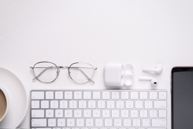 Photo of Flat lay composition with computer keyboard and smartphone on white table. Space for text