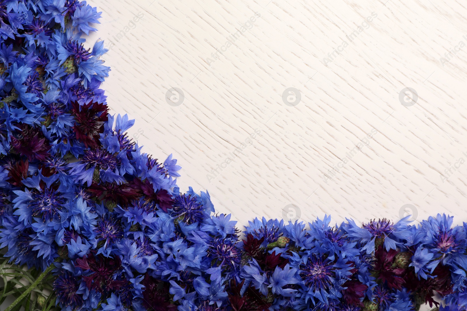 Photo of Beautiful blue cornflowers on white wooden table, flat lay. Space for text