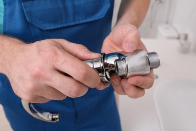 Photo of Professional plumber fixing water tap in bathroom, closeup