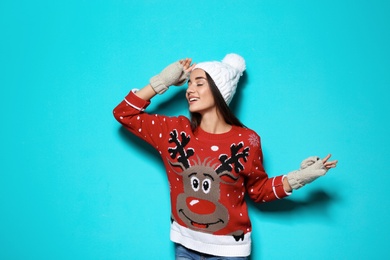 Photo of Young woman in Christmas sweater and knitted hat on color background