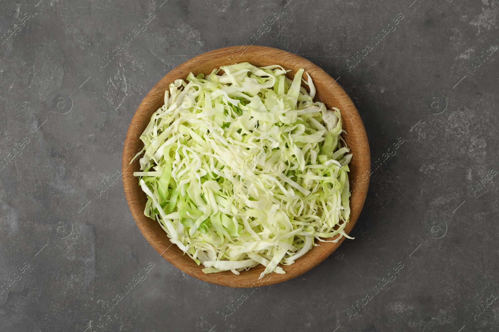 Photo of Chopped cabbage in bowl on grey table, top view