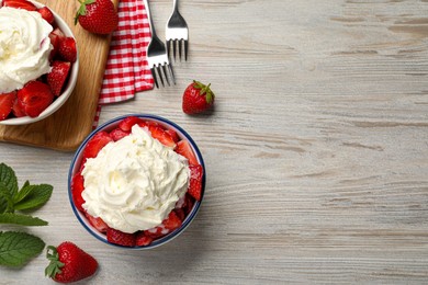 Photo of Delicious strawberries with whipped cream served on wooden table, flat lay. Space for text