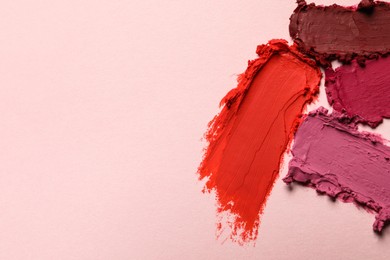Photo of Smears of different bright lipsticks on light background, top view. Space for text