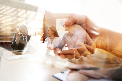 Double exposure of workers and business partners shaking hands in office, closeup 