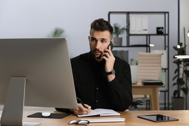 Man talking on phone while working at table in office