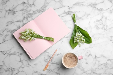 Photo of Flat lay composition with notebook, lily of the valley bouquets and coffee on marble background. Space for text