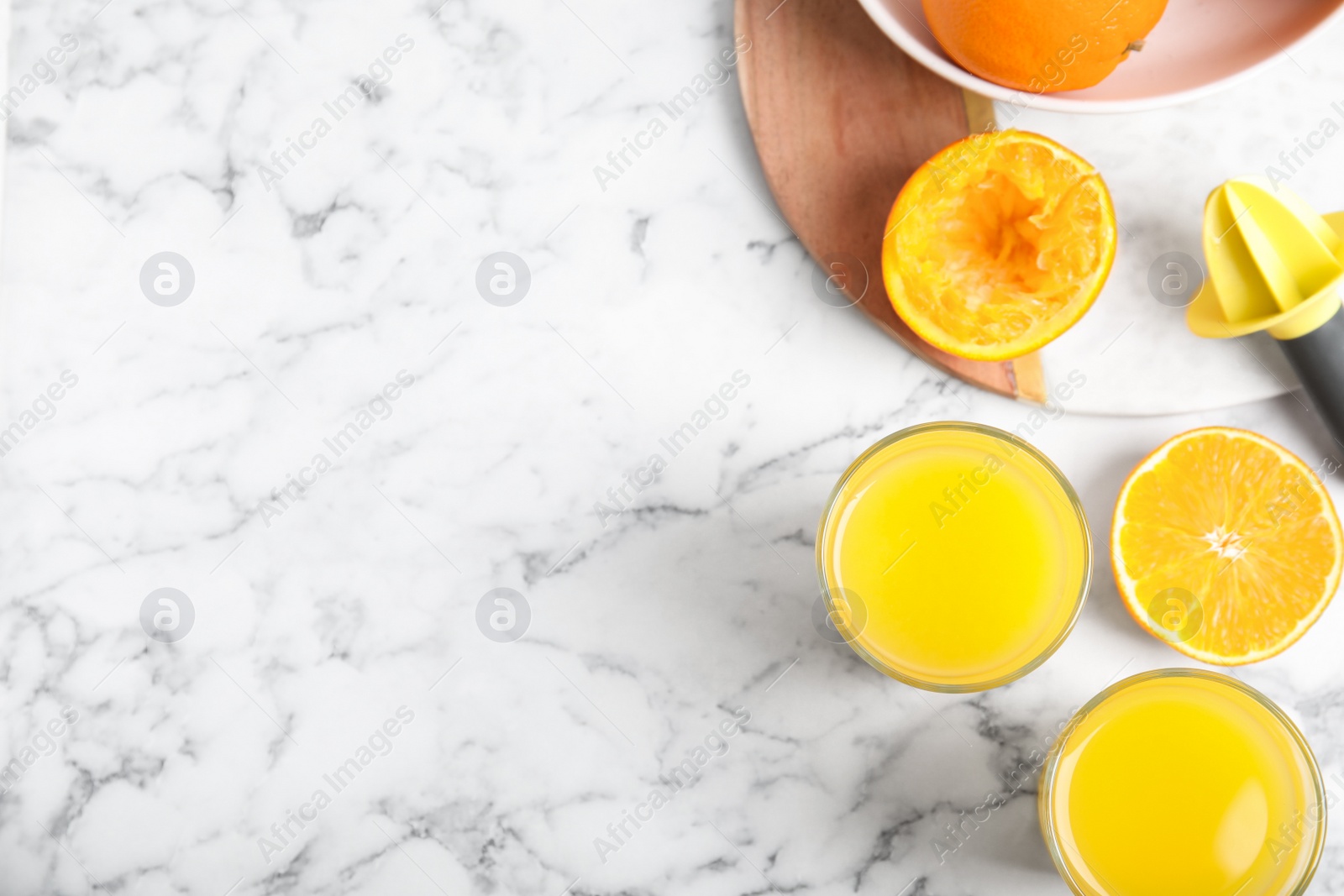 Photo of Fresh ripe orange, juice and reamer on white marble table, flat lay. Space for text