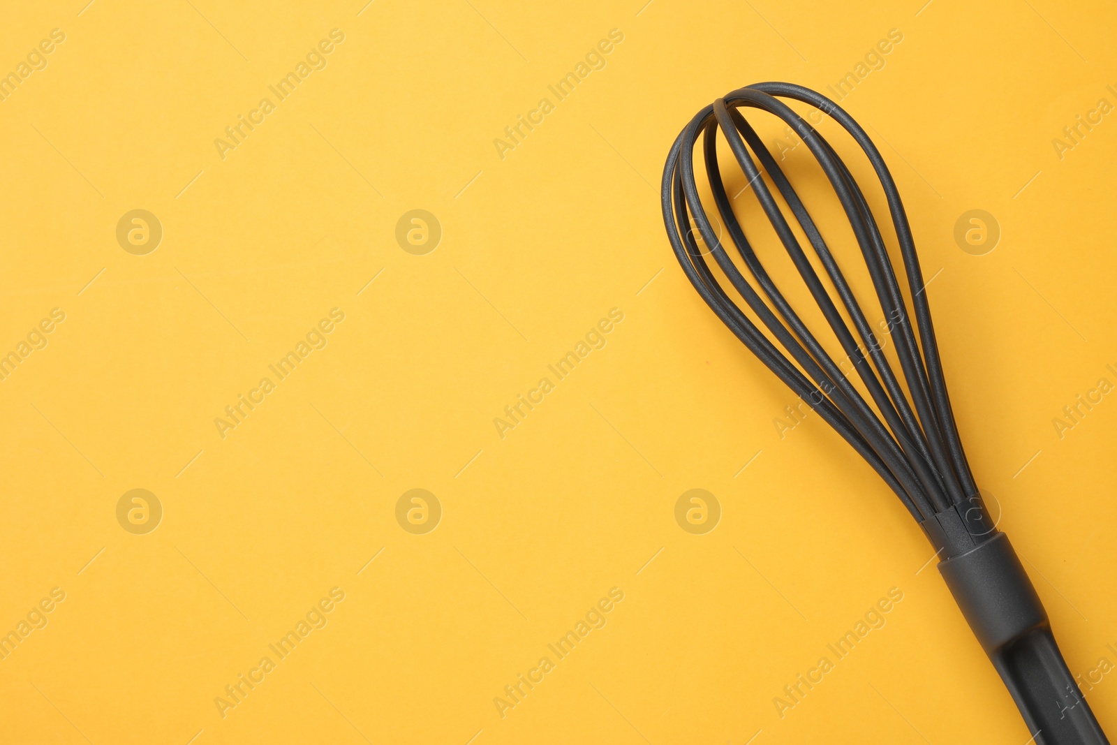 Photo of Plastic whisk on yellow background, top view. Space for text