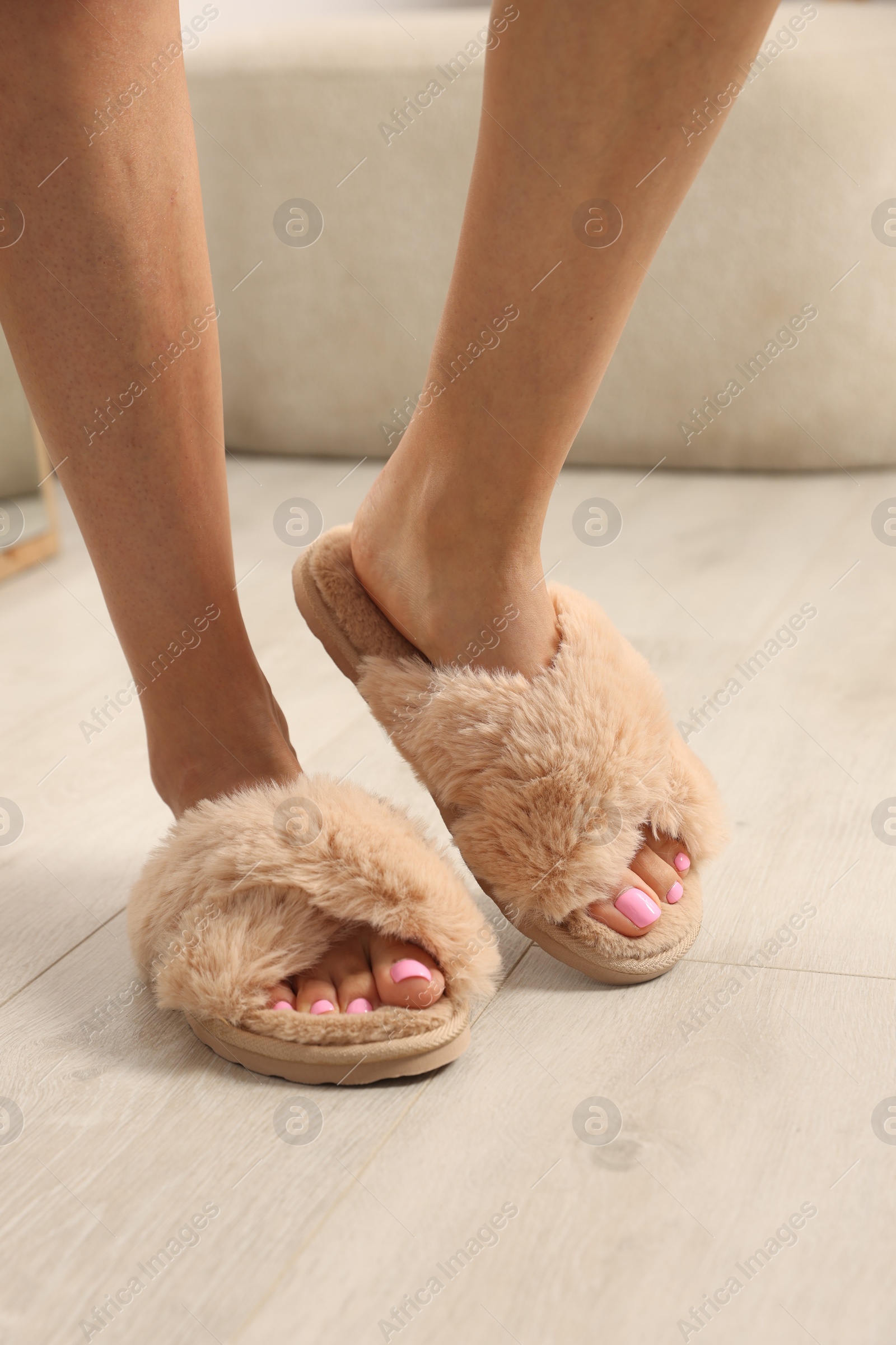 Photo of Woman wearing beige soft slippers indoors, closeup