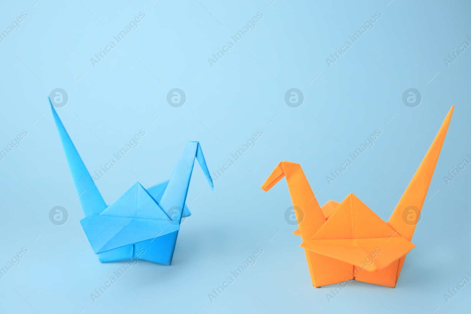 Photo of Origami art. Colorful handmade paper cranes on light blue background