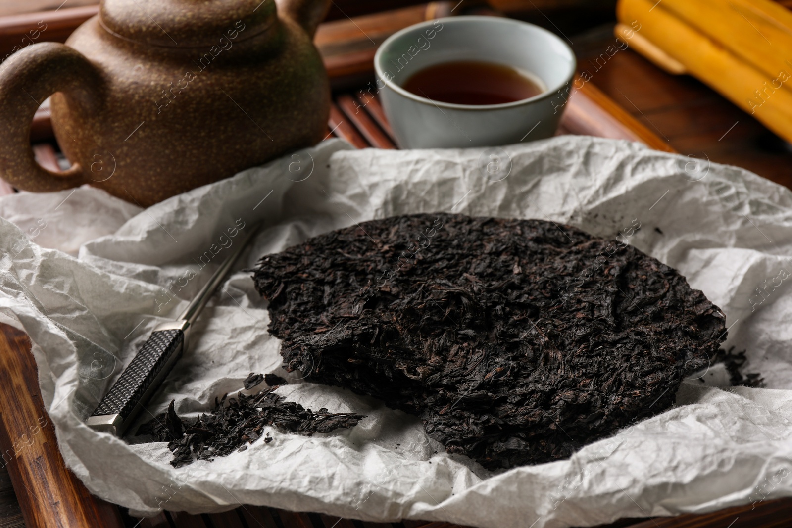 Photo of Broken disc shaped pu-erh tea and knife on wooden tray