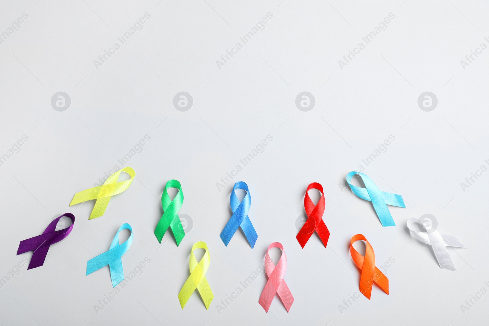 Photo of Different colorful ribbons on white background, flat lay with space for text. World Cancer Day